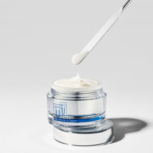 spatula scooping cu vitamin u cream moisturizer on a grey background.