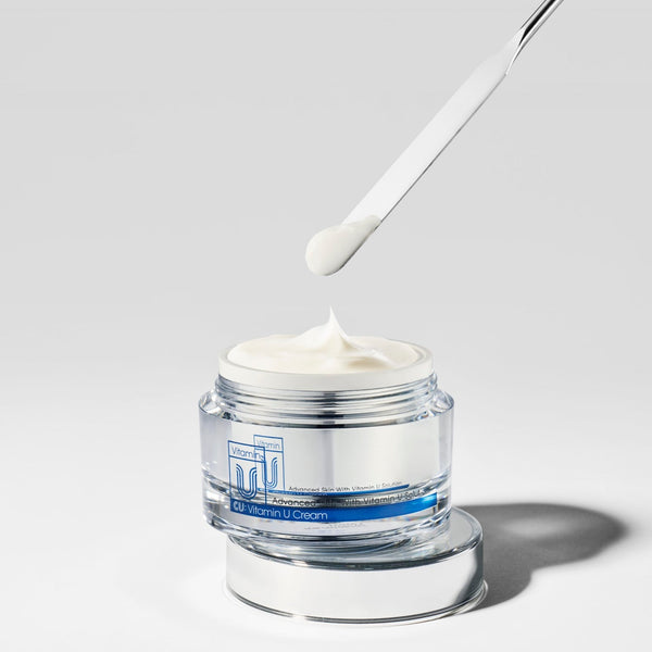 spatula scooping cu vitamin u cream moisturizer on a grey background.