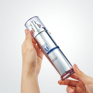 Hand holding a cu vitamin u toner silver skincare bottle with a blue label against a white background.