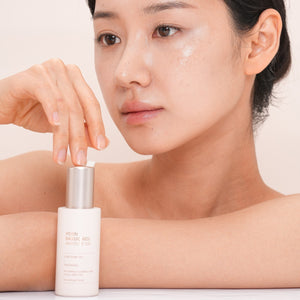 dr solution pdrn bakuchiol ampoule 100 serum woman applying skincare product to her face with a neutral background.